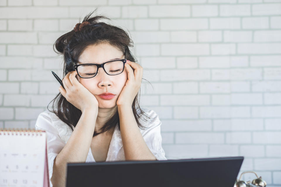 tired Asian woman sleepy taking a nap at work sitting at office desk