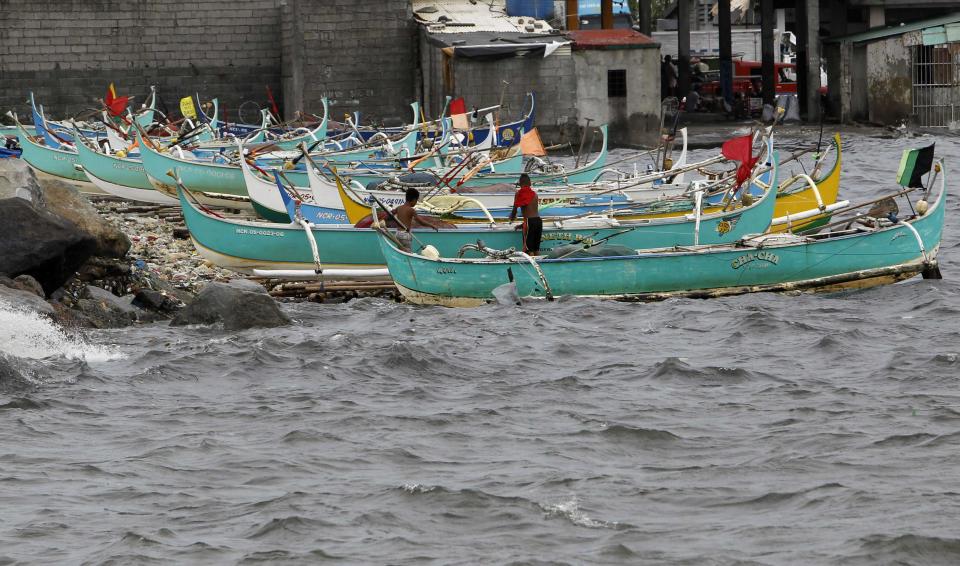 Fishermen secure ropes holding their boats as rough waves crash during Typhoon Usagi in Manila