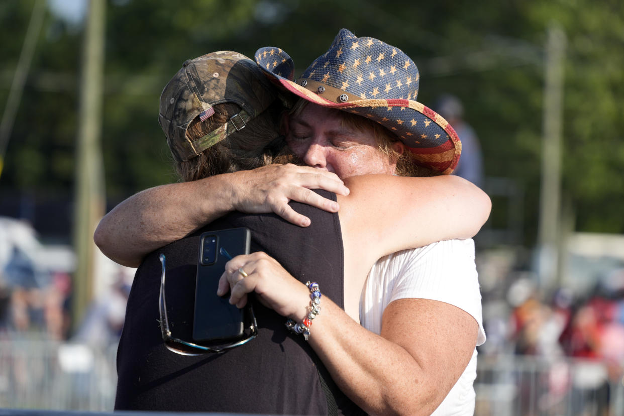 Two people wearing rally gear hug after Trump, who was wounded, was helped off the stage in Butler, Pa. 