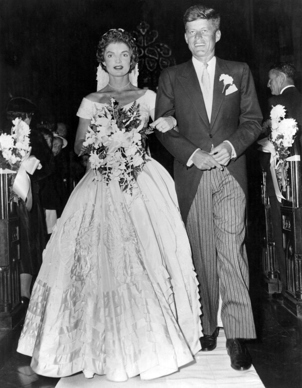 JFK escorts his bride Jacqueline Lee Bouvier down the church aisle shortly after their wedding ceremony at Newport, Rhode Island - Credit: Getty