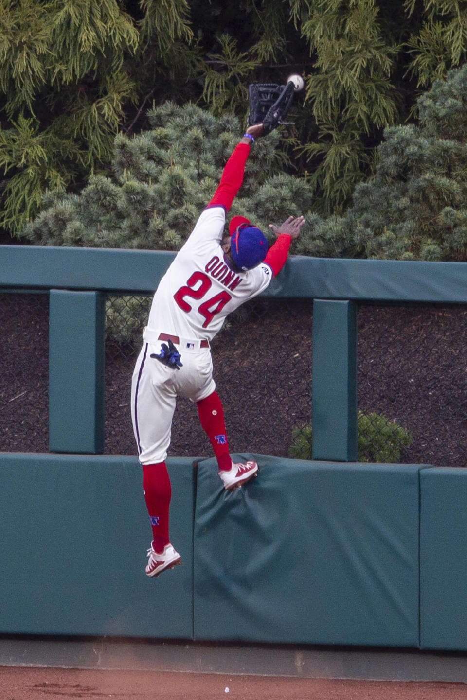 Philadelphia Phillies center fielder Roman Quinn goes over the fence trying to catch a home run by St. Louis Cardinals' Paul DeJong (11) during the third inning of a baseball game, Saturday, April 17, 2021, in Philadelphia. (AP Photo/Laurence Kesterson)