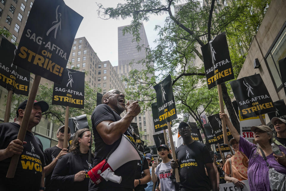 Ezra Knight, fourth from left, SAG-AFTRA union New York local president, uses a bullhorn to address striking writers and actors on a picket line, Friday July 14, 2023, at NBC Universal Studios in New York. (AP Photo/Bebeto Matthews)