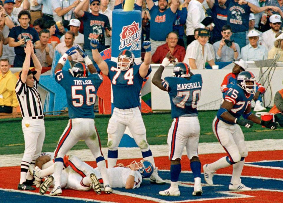 FILE - New York Giants defense Lawrence Taylor (56), Erik Howard (74) and Leonard Marshall (70) celebrate over Denver Broncos quarterback John Elway after he was sacked by George Martin (75) for a safety in the second quarter of NFL football's Super Bowl XXI game in Pasadena, Calif., Jan. 25, 1987. The Giants trailed Elway's Broncos 10-9 at halftime, but defeated Denver 39-20.(AP Photo/Ron Heflin, File)