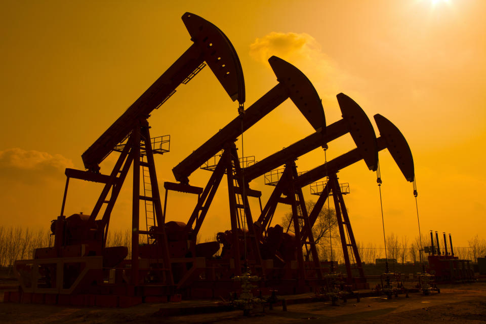 Four oil wells pumping under an orange sky.