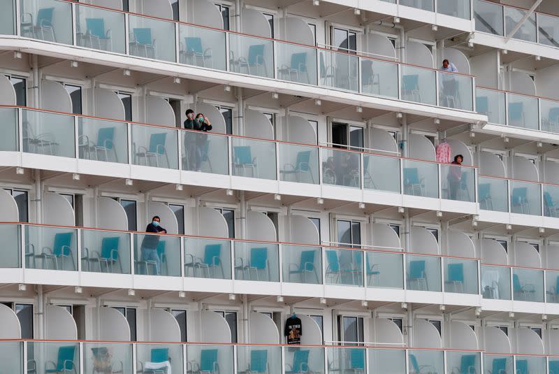 Passenger wearing face mask looks out from a cabin on the World Dream cruise ship, after it had been denied entry in Taiwan amid concerns of coronavirus infection on board, is seen docked at the Kai Tak Cruise Terminal in Hong Kong