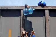 <p>Ein Migrant, der in einer Karawane durch Mexico unterwegs ist, reicht von einem Frachtenzug einen Wasserbehälter herunter. (Bild: REUTERS/Edgard Garrido) </p>