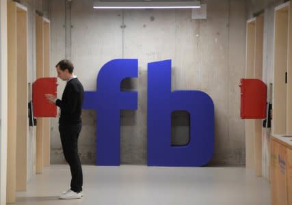 A man waits for an elevator in front of a logo at Facebook's headquarters in London, Britain, December 4, 2017. REUTERS/Toby Melville