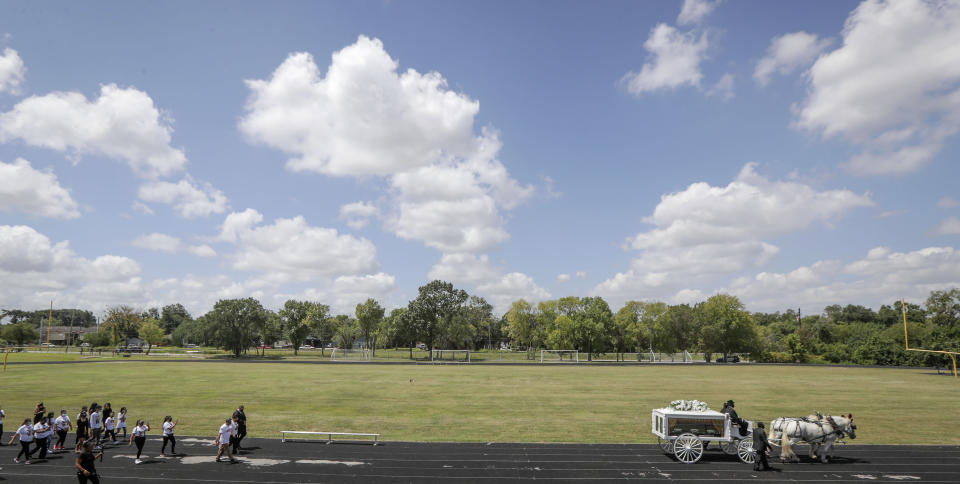 A horse draw carriage with the remains of U.S. Army Specialist Vanessa Guillen makes a final lap around the Cesar Chavez High School track Friday, Aug. 14, 2020, in Houston. Guillen, who was last seen on April 22, was laid to rest nearly four months after she is said to have been killed by a fellow soldier at Fort Hood, a U.S. Army base in Texas. Mourners gathered at the high school where Guillen grew up playing soccer and dreaming of joining the military. (Steve Gonzales/Houston Chronicle via AP)