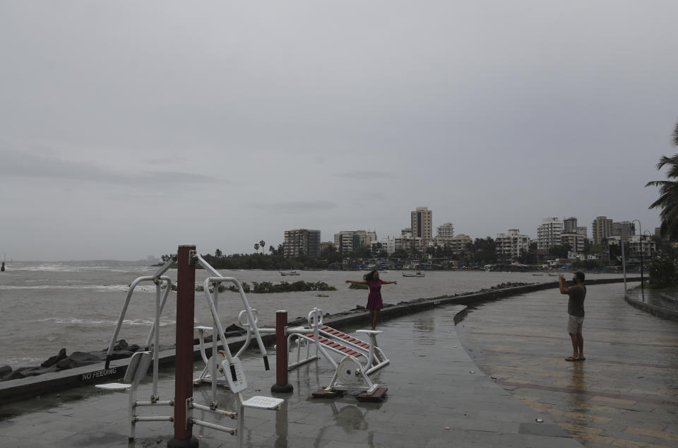 A man takes a photograph of a woman by the shores of the Arabian Sea in Mumbai, India, Wednesday, June 3, 2020. A storm in the Arabian Sea off India's west coast intensified into a severe cyclone on Wednesday, gathering speed as it barreled toward India's financial capital of Mumbai. Nisarga was forecast to drop heavy rains and winds gusting up to 120 kilometers (75 miles) per hour when it makes landfall Wednesday afternoon as a category 4 cyclone near the coastal city of Alibagh, about 98 kilometers (60 miles) south of Mumbai, India's Meteorological Department said. (AP Photo/Rafiq Maqbool)