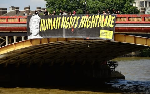 Amnesty International unveil a banner on the Vauxhall Bridge in London - Credit: Ian West /PA