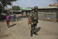 An Indian Border Security Force soldier stands at a Rohingya camp on the outskirts of Jammu, India, Sunday, March 7, 2021. Authorities in Indian-controlled Kashmir have sent at least 168 Rohingya refugees to a holding center in a process which they say is to deport thousands of the refugees living in the region. (AP Photo/Channi Anand)