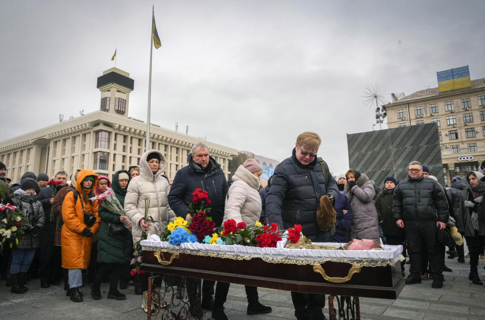 People pay their last respect at the coffin of Ukrainian soldier Oleh Yurchenko killed in a battlefield with Russian forces in the Donetsk region, during a commemoration ceremony in Independence Square in Kyiv, Ukraine, Sunday, Jan. 8, 2023. (AP Photo/Efrem Lukatsky)