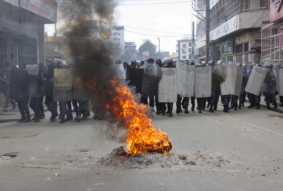Riot police behind a burning tyre keep an eye on anti-election protesters in Antananarivo, Saturday Nov. 11, 2023. Madagascar's Andry Rajoelina is pushing ahead with a presidential election, Thursday, Nov. 16 that could give him a third term, even as opposition protests roil the country and the majority of candidates have announced a boycott. (AP Photo/Alexander Joe)