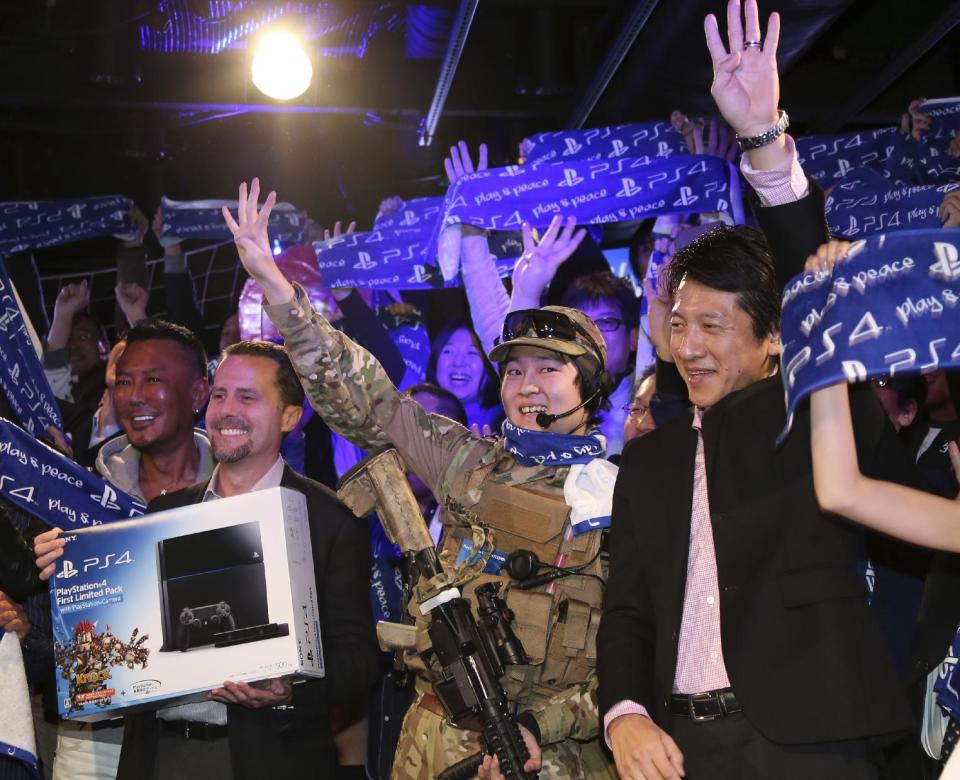 Sony Computer Entertainment Inc. President and CEO Andrew House, second left, Sony Computer Entertainment Japan President Hiroshi Kawano, right, and first customer of PlayStation 4 , center, pose for photo during launch event in Tokyo, Saturday, Feb. 22, 2014. (AP Photo/Koji Sasahara)