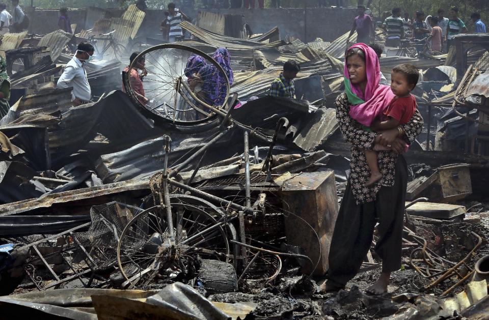 An Indian woman carries a child after their home was destroyed in a fire in New Delhi, India, Friday, April 25, 2014. A massive fire ripped through a New Delhi slum Friday, destroying nearly 500 thatched huts and leaving already impoverished families homeless, said a fire department official. Seven people were hospitalized with minor burn wounds. (AP Photo/Manish Swarup)