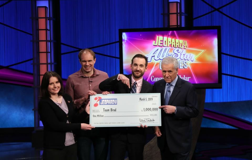 This photo provided by Sony shows Brad Rutter, Larissa Kelly and David Madden with Alex Trebek, winners of the first-ever "Jeopardy!" team championship, Tuesday, March 5, 2019 in in Burbank, Calif. With $1 million at stake, a big Daily Double bet by Rutter positioned his team for a runaway victory as the quiz show's "All-Star Games" ended Tuesday. Rutter and teammates Larissa Kelly and David Madden split the top prize. (Carol Kaelson /Sony via AP)
