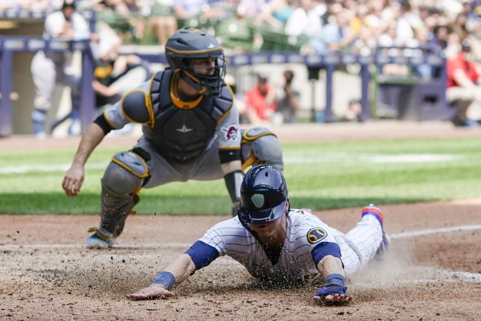 Milwaukee Brewers' Christian Yelich slides safely past Pittsburgh Pirates catcher Jason Delay during the fifth inning of a baseball game Sunday, June 18, 2023, in Milwaukee. Yelich scored from second on a hit by Jesse Winkler. (AP Photo/Morry Gash)