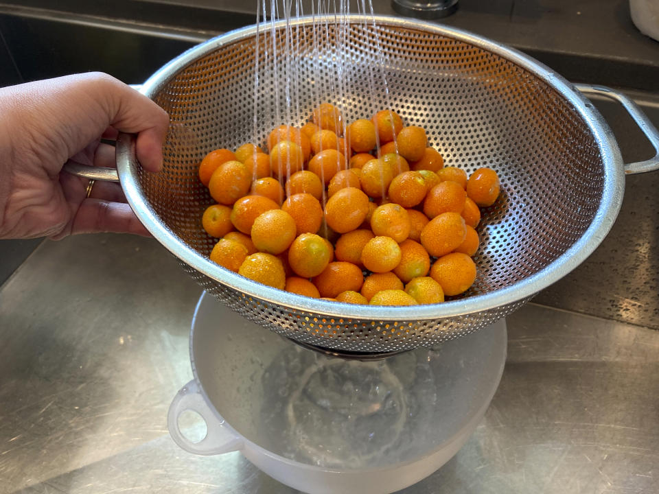 Kumquats are rinsed in a colander as the water is collected in a bowl on Thursday, June 30, 2022, at a home in Los Angeles. Water used for rinsing fruits and vegetables can be collected and used to water plants. (AP Photo/Paula Munoz)