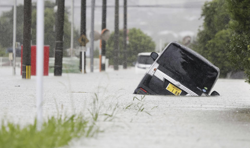 A vehicle is stuck on a street flooded due to a heavy rain in Kurume, Fukuoka prefecture, southern Japan Monday, July 10, 2023. Torrential rain is pounding southwestern Japan, triggering floods and mudslides Monday as weather officials issued emergency heavy rain warning in parts of on the southern most main island of Kyushu. (Kyodo News via AP)