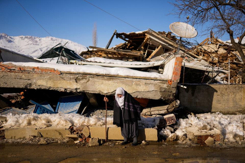 Zehra Kurukafa walks past a destroyed house in the village of Polat, Turkey, Sunday, Feb. 12, 2023