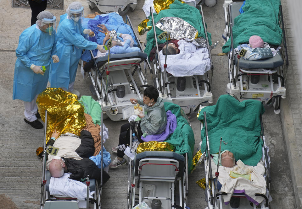 Patients lie on hospital beds as they wait at a temporary holding area outside Caritas Medical Centre in Hong Kong Wednesday, Feb.16, 2022. There was visible evidence that Hong Kong hospitals were becoming overwhelmed by the latest COVID surge, with patients on stretchers and in tents being seen to by medical personnel on Wednesday outside the Caritas hospital. (AP Photo Vincent Yu)