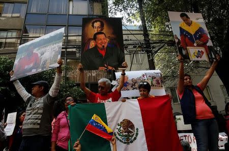 Supporters of Venezuelan President Nicolas Maduro hold up pictures of Venezuela's late president Hugo Chavez, during an event in favor of Venezuela's Constituent Assembly election, outside Venezuela's embassy in Mexico City, Mexico July 30, 2017. REUTERS/Henry Romero