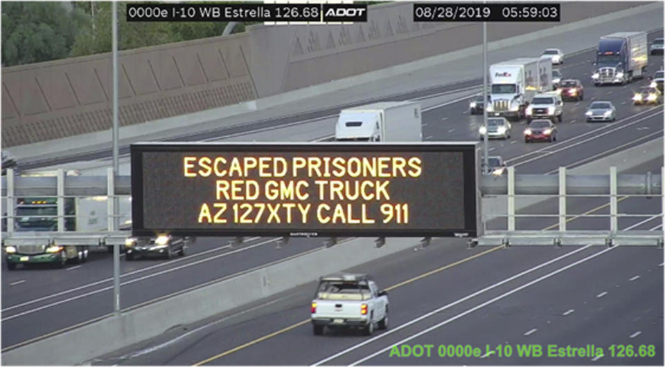 This photo from an Arizona Department of Transportation remote camera shows a digital sign over Interstate 10 in the Phoenix metropolitan area that seeks the public's help in locating escaped murder suspects,Wednesday, Aug. 28, 2019. These signs on Arizona highways alert the public that a married couple suspected in a Tucson killing remained at large after overpowering two guards and escaping while being extradited from New York to Arizona. Tucson police said 56-year-old Blane Barksdale and 59-year-old wife Susan Barksdale escaped Monday evening in Blanding, Utah. (Arizona Department of Transportation via AP)