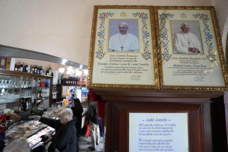 Photos of Pope Francis and late Pope Emeritus Benedict XVI are displayed in a cafe in Castel Gandolfo, in the hills south of Rome, Tuesday Jan. 3, 2023. Benedict's death has hit Castel Gandolfo's "castellani" particularly hard, since many knew him personally, and in some ways had already bid him an emotional farewell on Feb. 28, 2013, when he uttered his final words as pope from the palace balcony overlooking the town square. (AP Photo/Alessandra Tarantino)