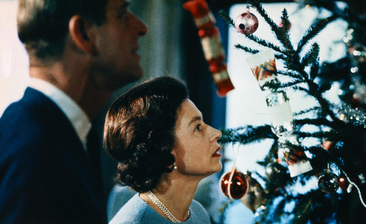 (Original Caption) Christmas at Windsor Castle is shown here with Queen Elizabeth II and Prince Philip shown putting finishing touches to Christmas tree, in a poto made recently during the filming of the joint ITV-BBC film documentary, The Royal Family.