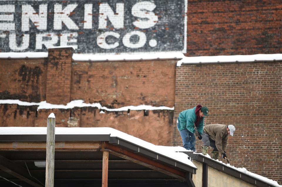 Workers clear ice and snow from the gutters of the O.P Jenkins building in Old City, Thursday, Jan. 18, 2024. More inclement weather is expected tonight.
