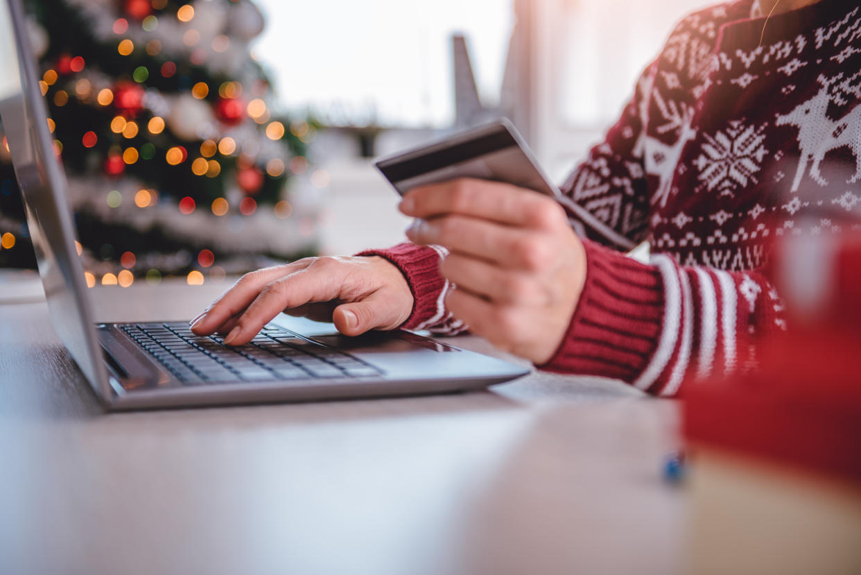 Women wearing red sweater shopping online and using credit card at home office debt