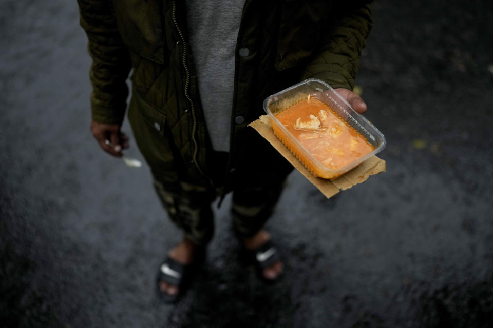 A resident holds a container of chicken stew that he received from the Excluded Workers Movement soup kitchen, in Buenos Aires, Argentina, March 13, 2024. Organizers said the kitchen is open three days a week and serves about 4,000 people a day, but because of the increasing number of people coming for meals, they often don't have enough to go around. (AP Photo/Natacha Pisarenko)