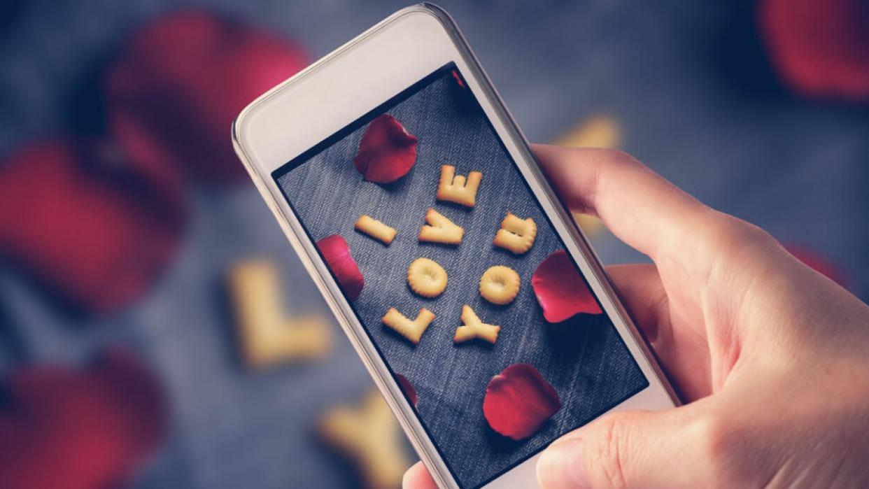 A person takes a picture with their phone of a message that says "I love you."