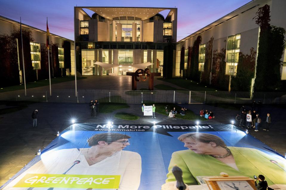 In this Thursday, Sept. 19, 2019 photo a giant poster showing German Chacellor Angela Merkel, right, and the chairwomen of the German Christian Democratic Party (CDU), Annegret Kramp-Karrenbauer, left, is displayed in front of the Chancellery in Berlin, Germany. The German government is scrambling to agree a package of measures for tackling global warming, as protesters prepare to stage rallies across the country demanding decisive action against climate change. (Kay Nietfeld/dpa via AP)