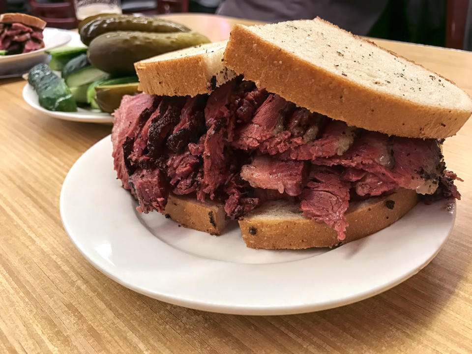 Pastrami sandwich and pickles on a table