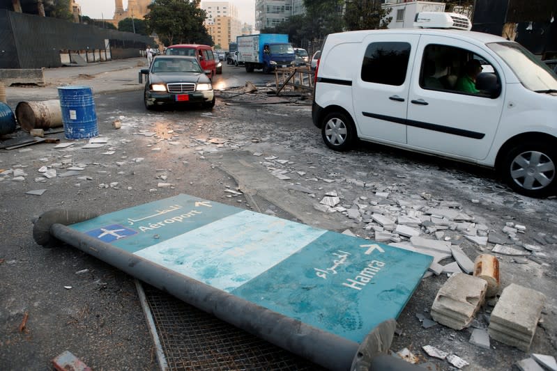 Cars drive past debris at a site of protest that happened yesterday over deteriorating economic situation