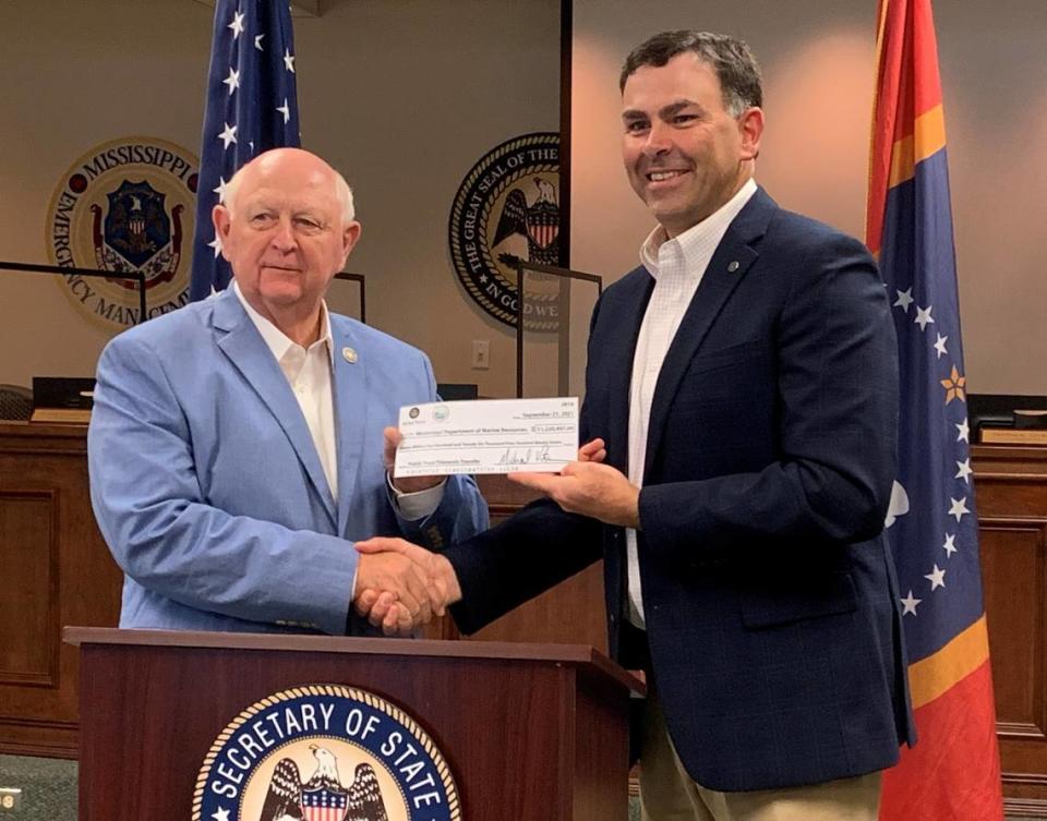 Secretary of State Michael Watson, right, hands a check for $11.2 million to Joe Spraggins, executive director of the Department of Marine Resources, on Sept. 21, 2021. The transfer of Tidelands Trust Funds pays for piers, parks and other projects coastwide.