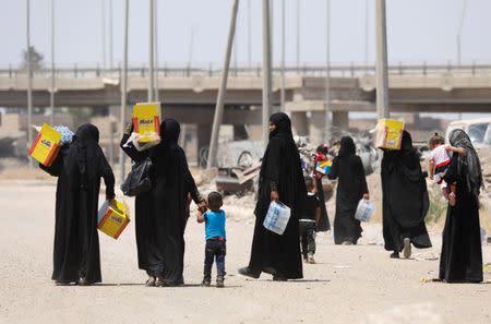 Displaced Iraqi residents carry boxes of biscuits and bottles of water given by an aid organization during the first day of Eid-al Fitr celebration in West Mosul, Iraq June 25, 2017. REUTERS/Erik De Castro