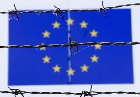 A barbed wire is seen in front of a European Union flag at an immigration reception centre in Bicske, Hungary June 25, 2015. REUTERS/Laszlo Balogh