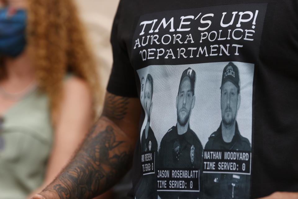 At a news conference in Aurora, Colo. in July 2020, a protester wears a shirt with photographs of the police officers involved in the fatal encounter with Elijah McClain.