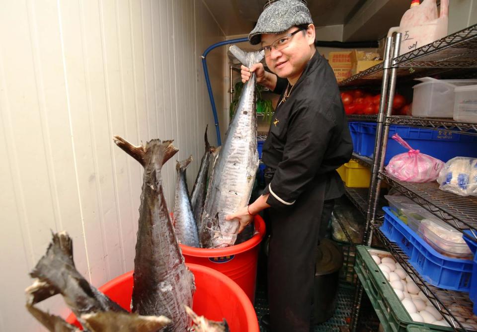 陳博璿手拿3、40斤重的土魠魚，為求品質，他們自己進貨再分切。