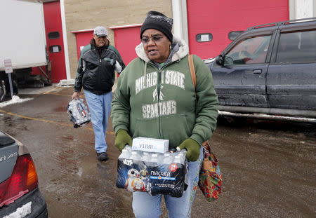 Flint resident Ruby Adolph carries bottled water and a replacement water filter she received at a fire station in Flint, Michigan January 13, 2016. REUTERS/Rebecca Cook