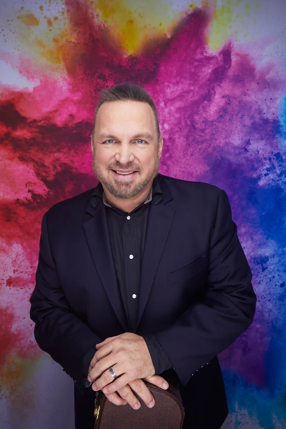 garth brooks posing with his hands on his knee and smiling for a promotional picture