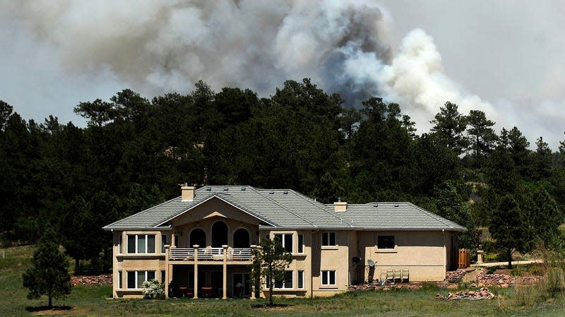 Smoke billows near a home from the Black Forest Fire on June 12, 2013 north of Colorado Springs, Colorado.