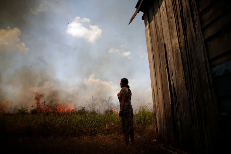 Miraceli de Oliveira reacts as the fire approaches their house in an area of the Amazon rainforest, near Porto Velho