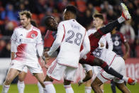 Toronto FC's Prince Osei Owusu (99) tumbles as he scores, while New England Revolution's Mark-Anthony Kaye (28) watches during the second half of an MLS soccer match Saturday, April 20, 2024, in Toronto. (Frank Gunn/The Canadian Press via AP)