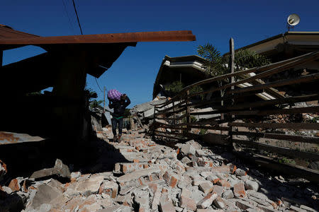A man carries his belonging as he walks near the ruins of a mosque after an earthquake hit on Sunday in Pemenang, Lombok island, Indonesia, August 7, 2018. REUTERS/Beawiharta