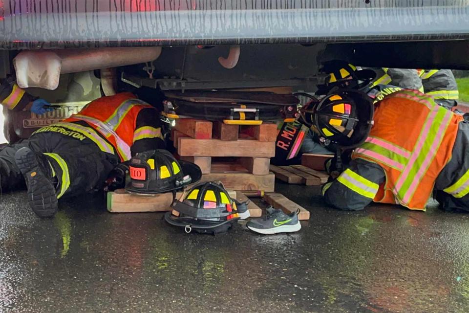 <p>Vancouver Fire Department</p> Photo of fire fighters working under the school bus after the incident