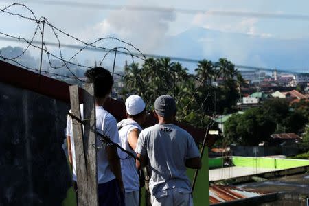 Men watch from a rooftop during the Philippines army airstrike as government troops continue their assault against insurgents from the Maute group in Marawi city June 27, 2017. REUTERS/Jorge Silva