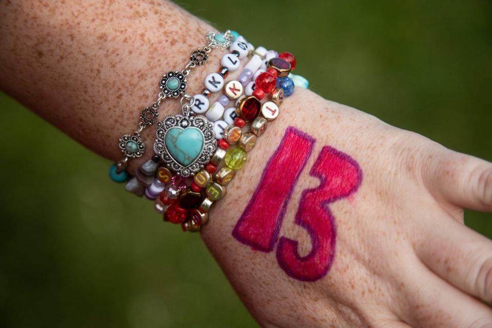 Emily Schenk, 30, of Milford, shows off the bracelets that she and her friends made with Taylor Swift's lyric and the singer's lucky number 13 drawn on the back of her left hand at Central Park in Milford on Tuesday, June 6, 2023.